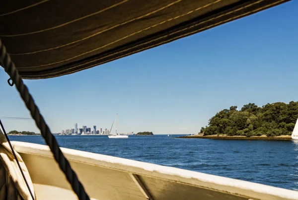 A view of Boston Harbor from a boat showing the skyline and harbor islands on a sunny day