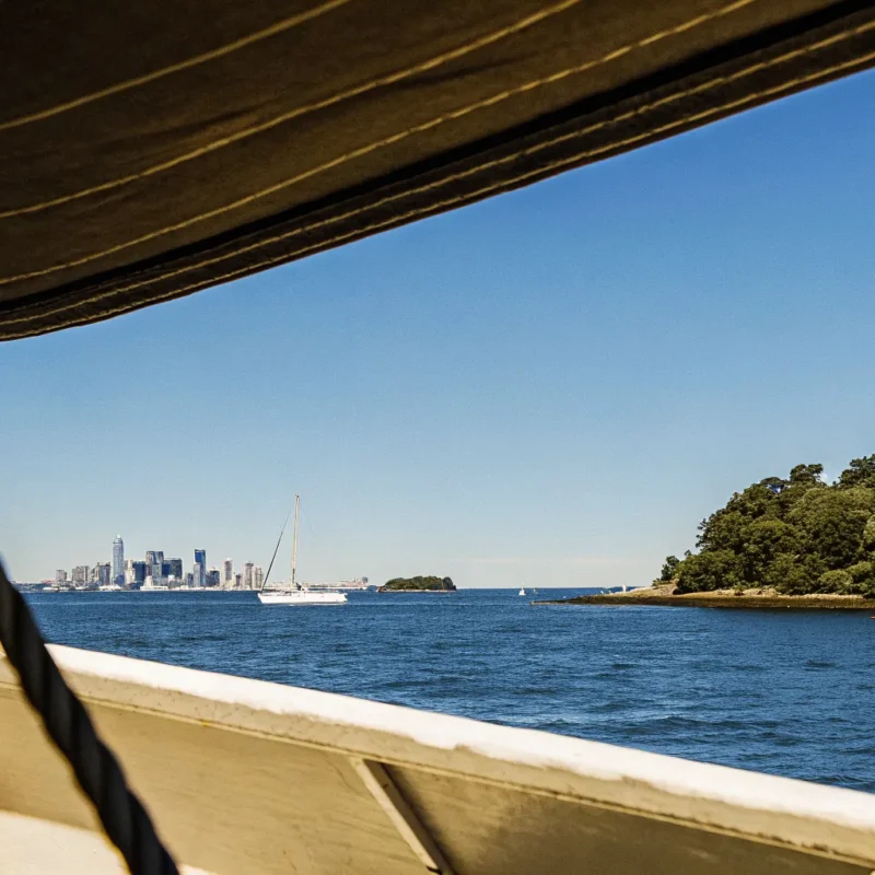 A view of Boston Harbor from a boat showing the skyline and harbor islands on a sunny day