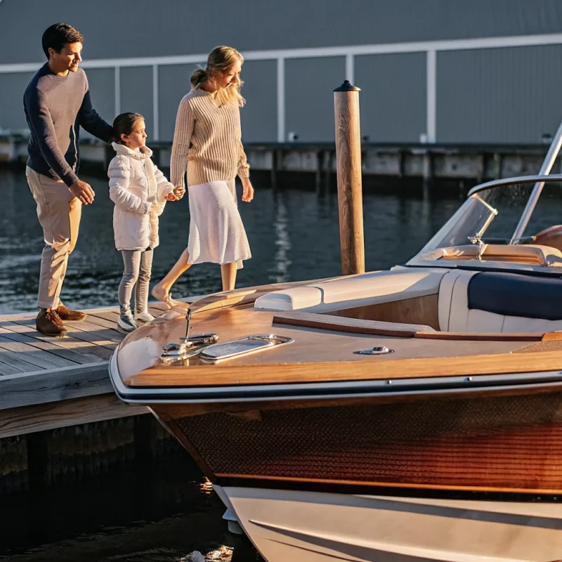 Family standing beside a boat at a New England marina during golden hour