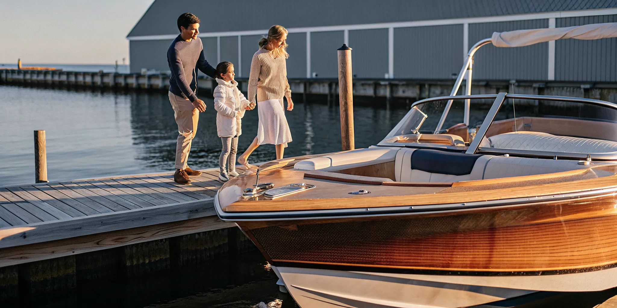 Family standing beside a boat at a New England marina during golden hour