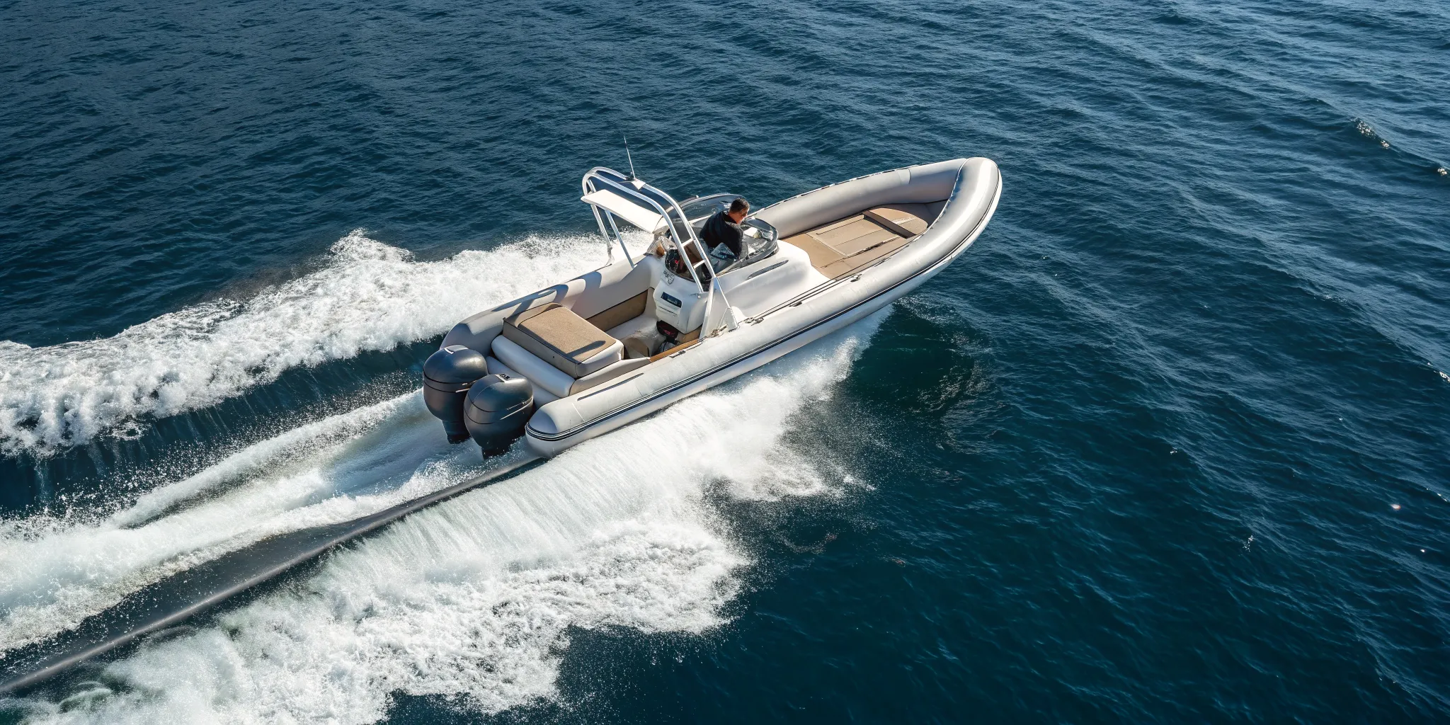 A fast RIB boat with twin engines speeds across the open water.